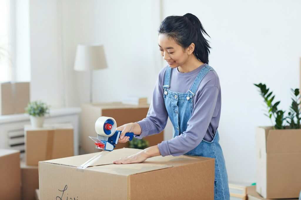Asian Woman Packing Boxes for Moving Out