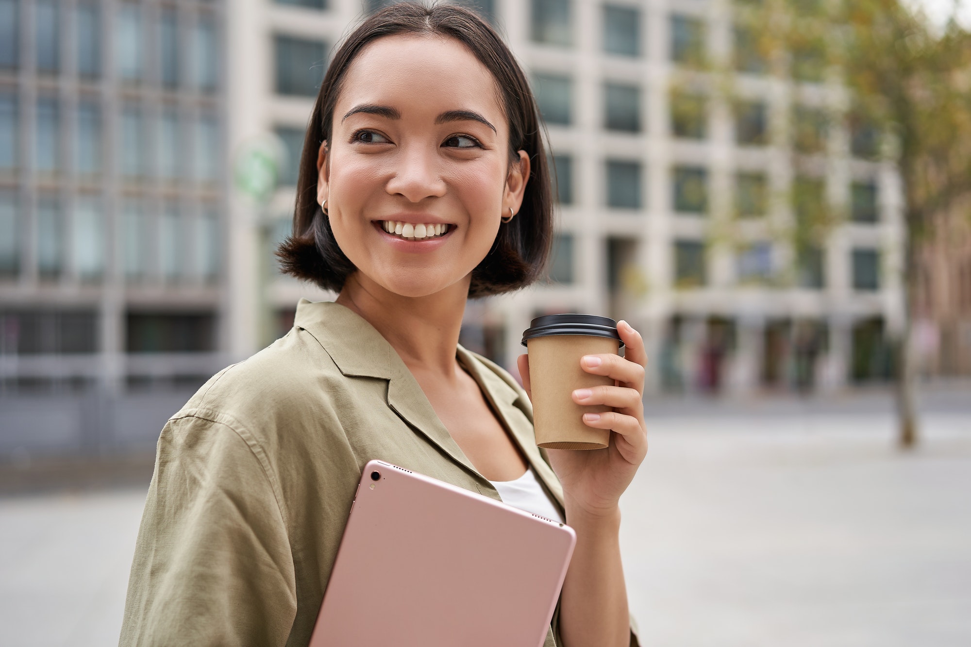Portrait of asian girl with tablet, drinks coffee on street, walking in city centre