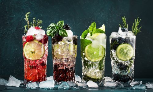 Cocktails drinks. Classic alcoholic long drink or mocktail highballs with berries, lime, herbs